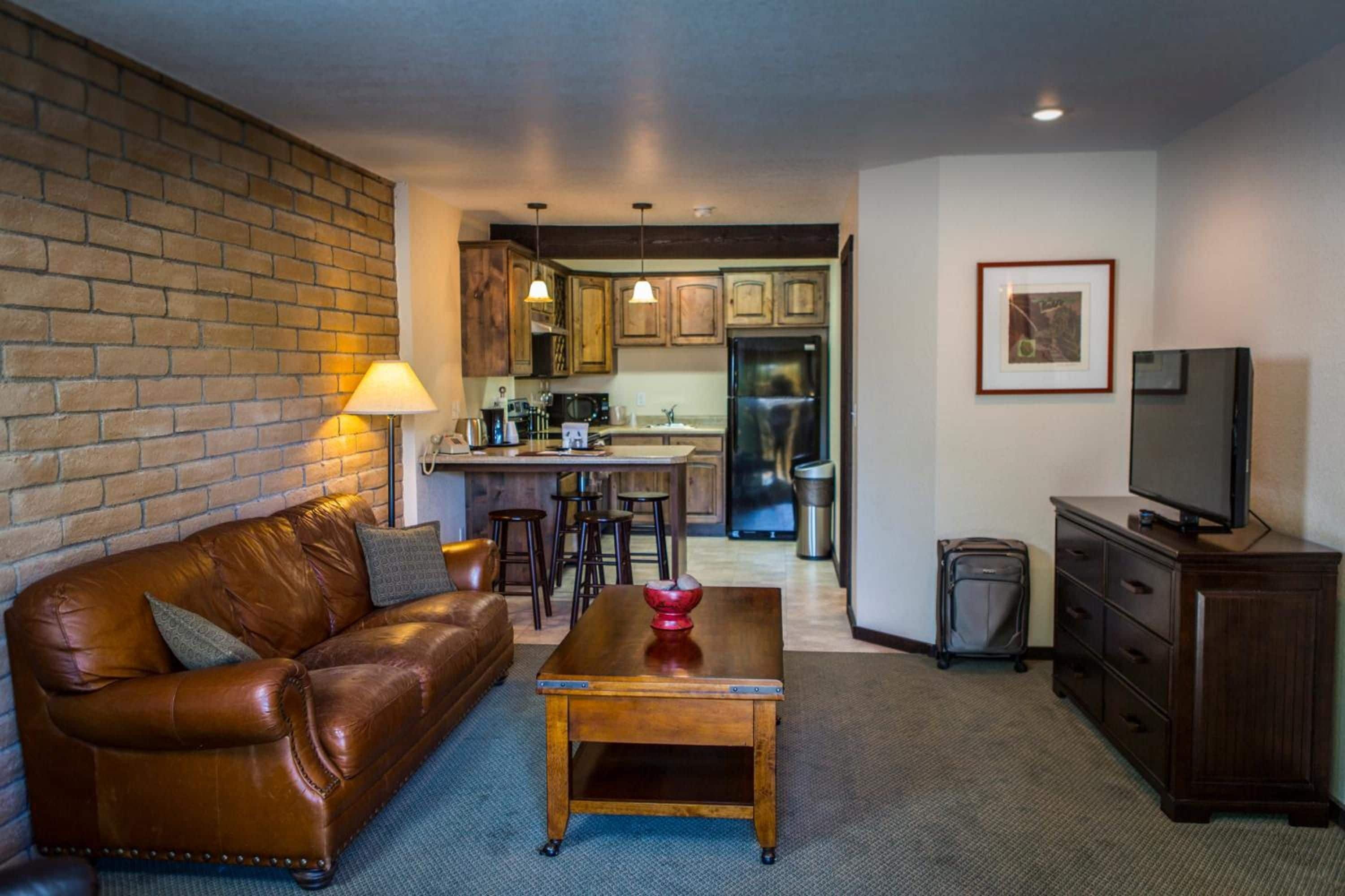 A living room with a leather sofa, a wooden coffee table, and a TV on a cabinet.