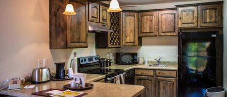 A kitchen with wooden cabinets, a stainless steel refrigerator, a microwave, and a stove.
