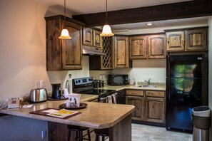 Una cocina con gabinetes de madera, un refrigerador de acero inoxidable, un microondas y una estufa.