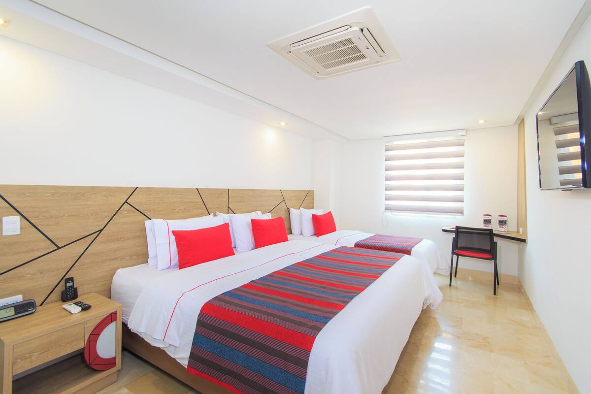 A modern hotel room with a large bed, a desk, and a TV.