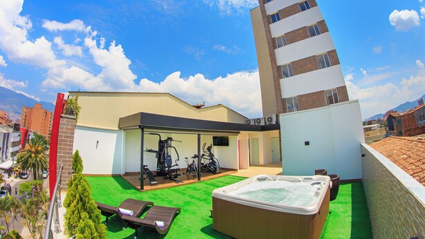 Un edificio moderno con patio en la azotea, gimnasio al aire libre y bañera de hidromasaje.