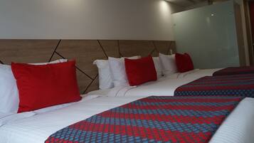 A hotel room with two beds, red and white bedding, and a wooden headboard.