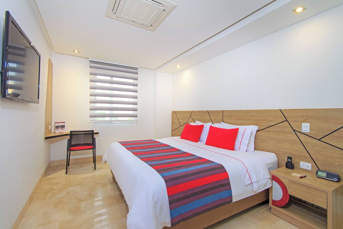 A modern hotel room with a large bed, a desk, and a chair.