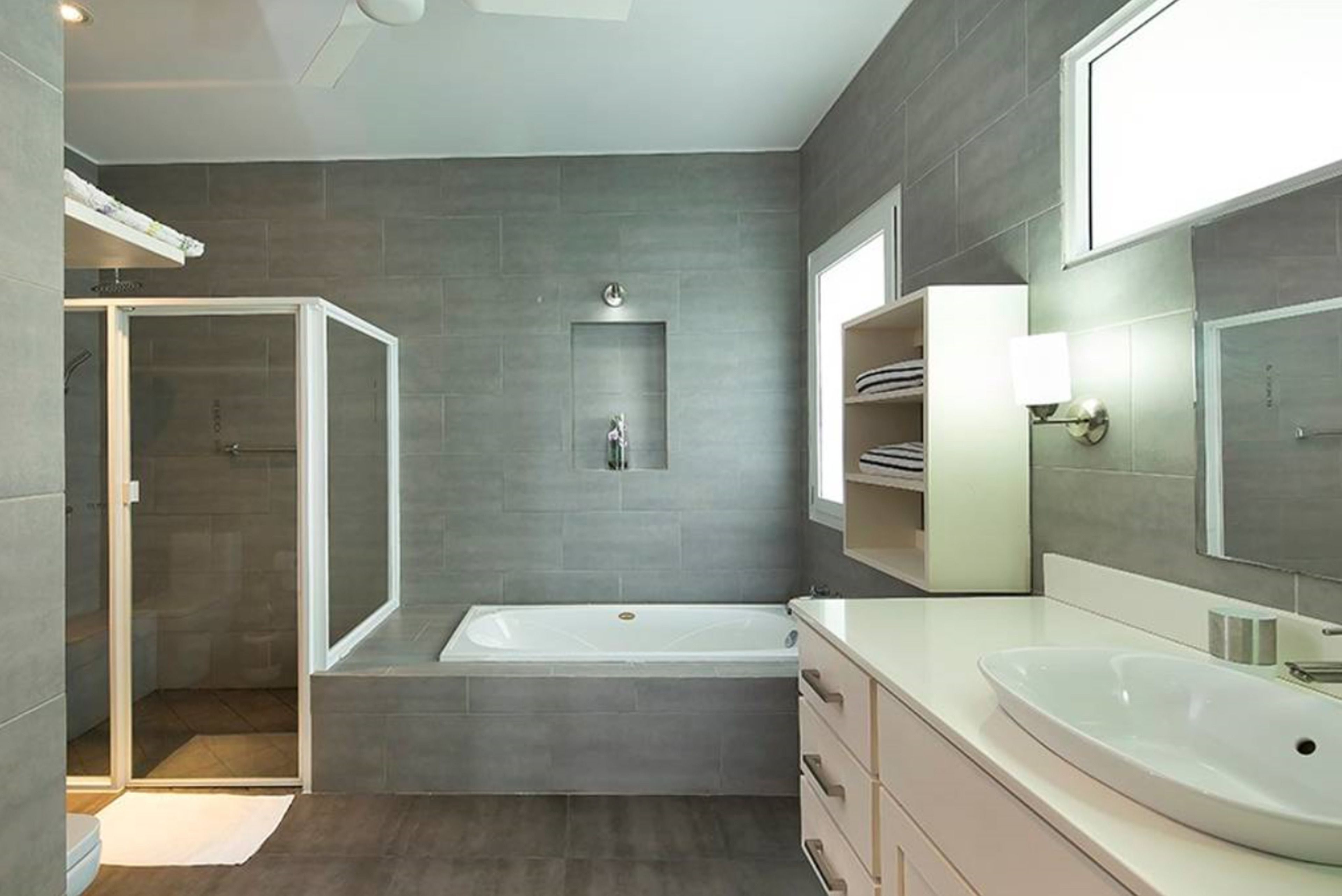 A modern bathroom with a walk-in shower, a freestanding bathtub, and a vanity with a large mirror.