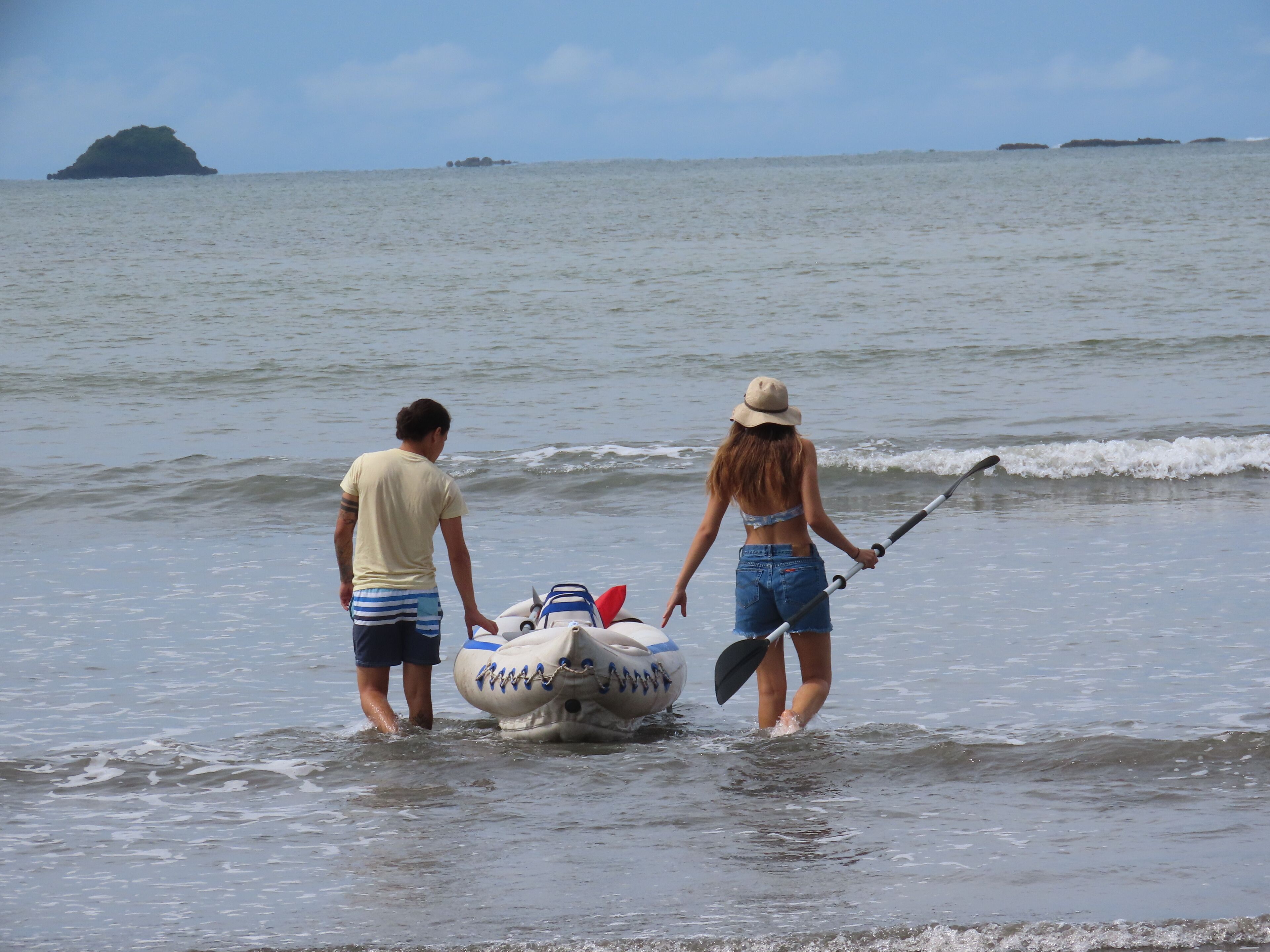 Two people standing in shallow water with a boat.