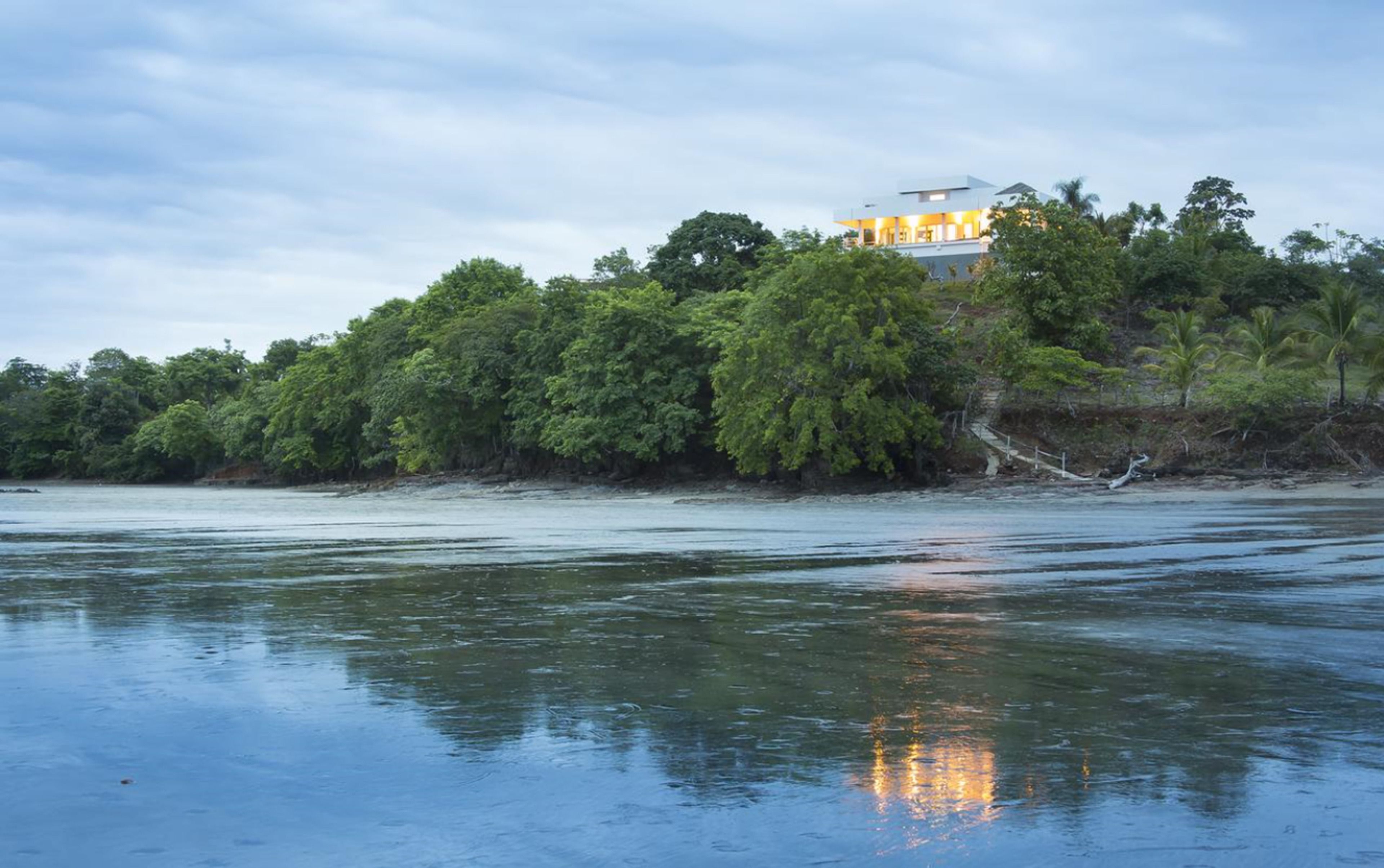 A beachfront property with a large house surrounded by dense tropical vegetation.