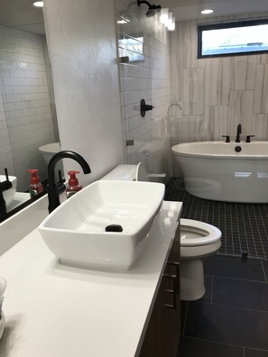 A modern bathroom with a large rectangular sink, a toilet, and a bathtub.
