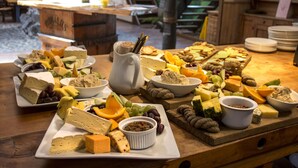 A variety of cheeses, fruits, and nuts arranged on a wooden table in a rustic setting. - River Valley Lodge (Pukeokahu)