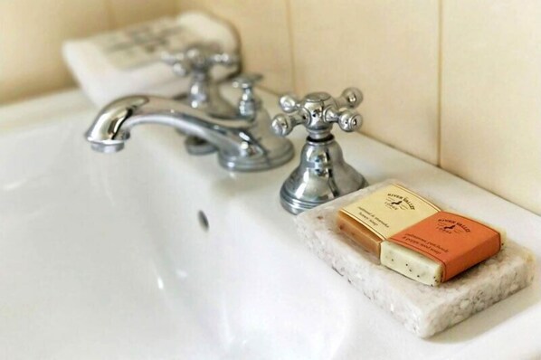 A bathroom sink with two faucets and a bar of soap on a marble soap dish.