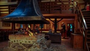 A stone fireplace with a blue chimney, wooden benches, and a staircase leading to an upper level. - River Valley Lodge (Pukeokahu)