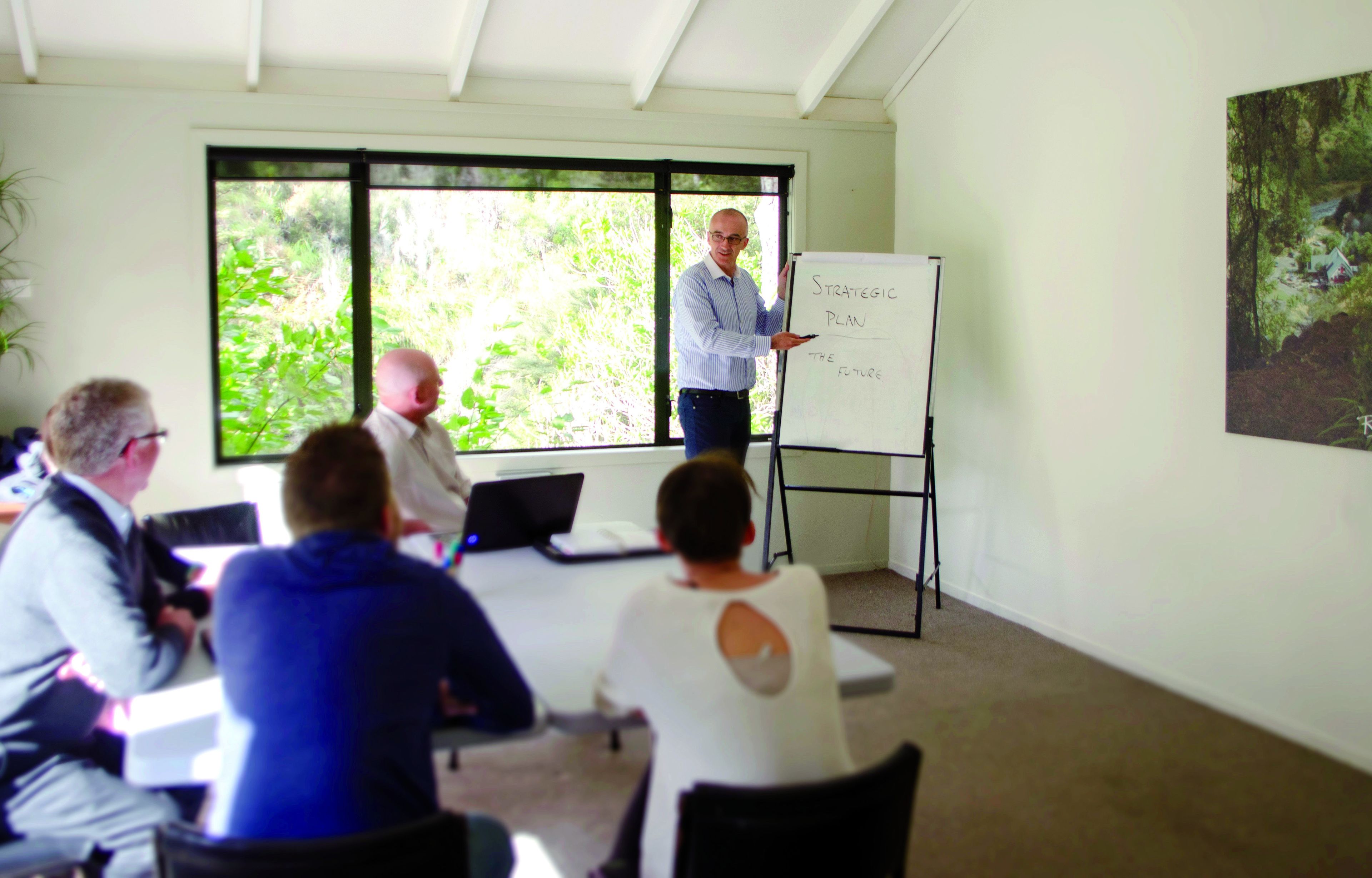 A meeting room with a whiteboard, a large window, and a painting on the wall.