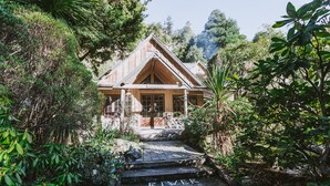 A wooden cabin with a steep staircase leading up to it, surrounded by lush greenery. - River Valley Lodge (Pukeokahu)