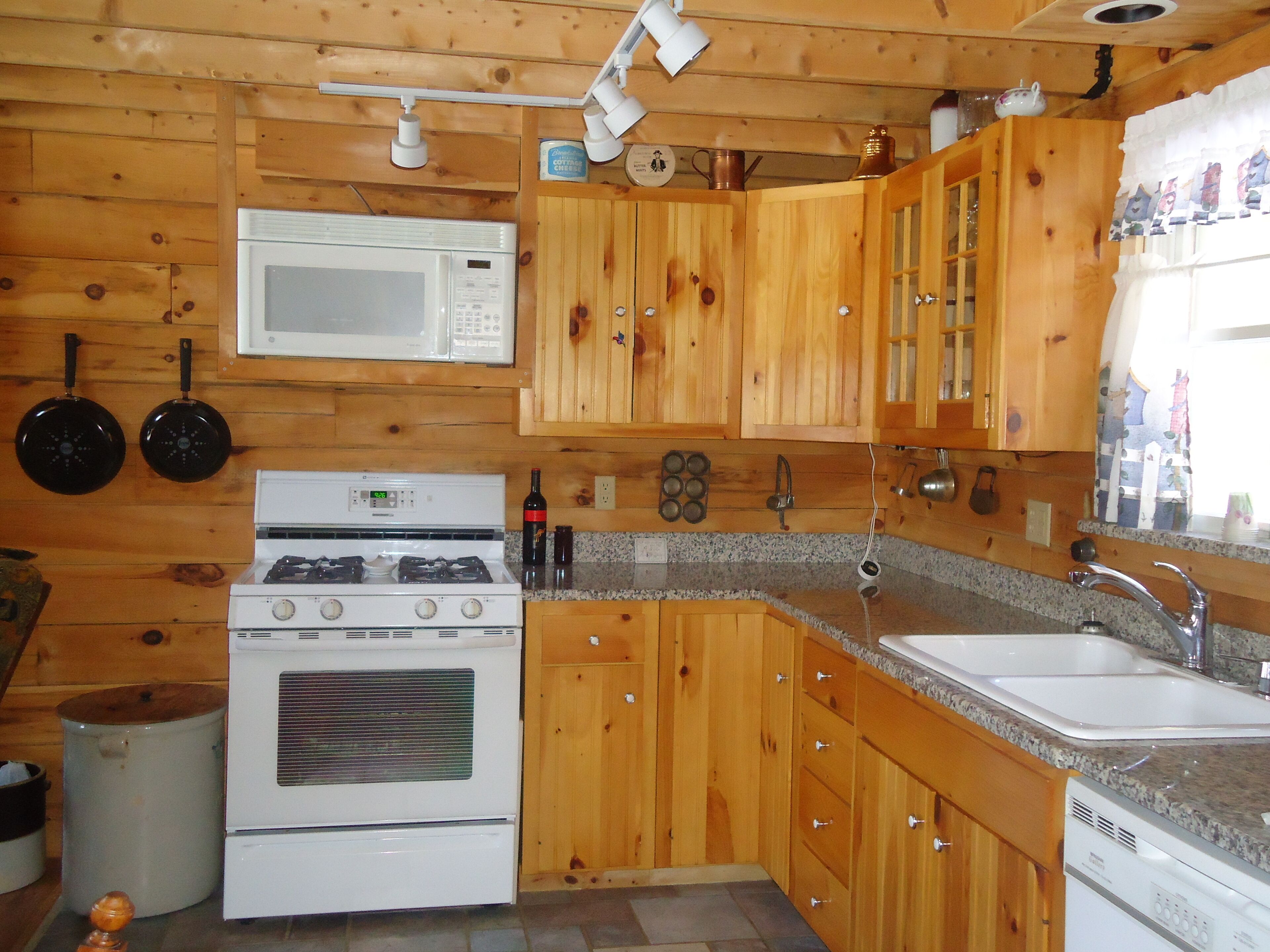 A kitchen with wooden cabinets, a stove, a microwave, and a sink.