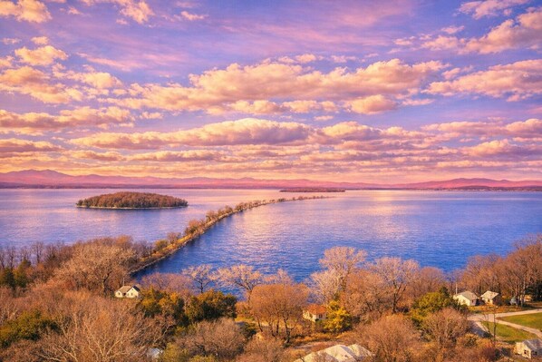 A lakeside view with a dock, houses, and a distant island. - Causeway Bike Path steps away with Water access and Kayaks. (Colchester)