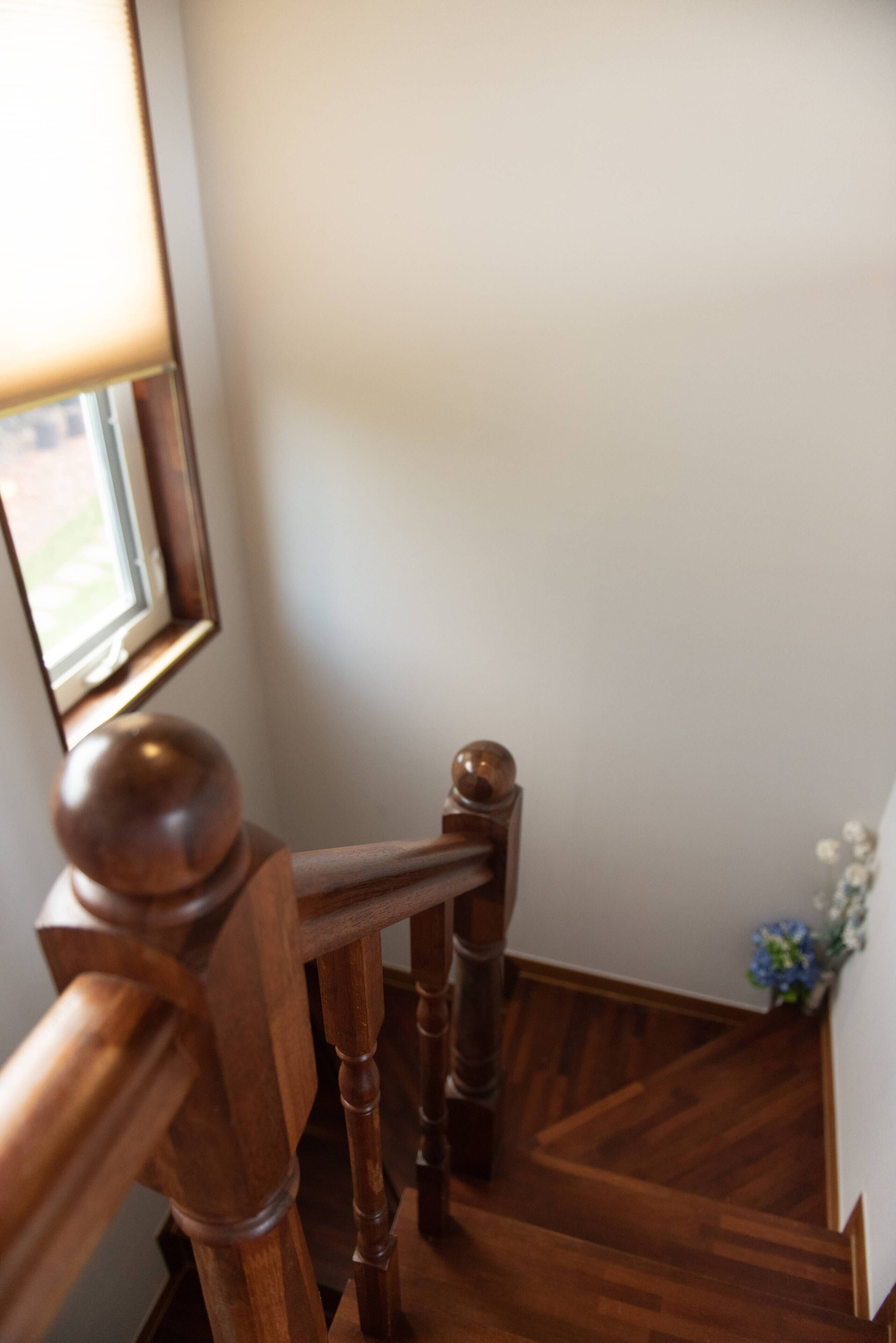 Un escalier en bois, doté d’une rampe et d’une petite fenêtre en haut.