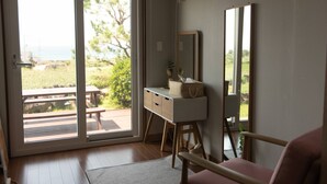 Une pièce dotée d’une porte-fenêtre coulissante donnant sur un espace extérieur aménagé avec une table de pique-nique et de la verdure.