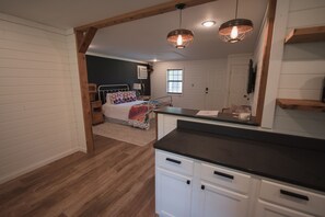 A bedroom with a bed, bedside table, and a nightstand. There is a window and a door in the room.