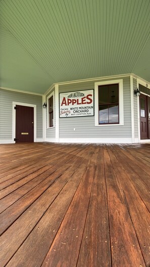 Een veranda met een houten vloer en een bordje waarop 'High Altitude Apples' van de White Mountain Orchard staat aangegeven.