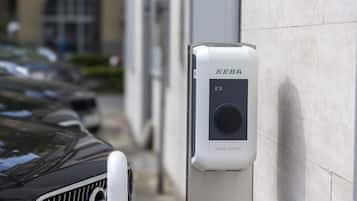 A KEBA Green Edition parking ticket machine mounted on a wall beside a car.