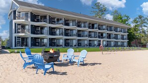 Et hotel med flere etager, altaner, grillområde og strandstole.