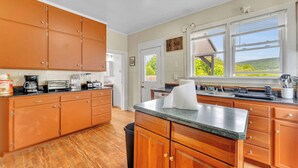 A kitchen with wooden cabinets, a granite countertop, and a view of the outdoors. - Left Field - All Star Baseball Rentals (Oneonta)