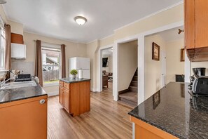 A modern kitchen with a central island, wooden cabinets, and a black granite countertop.