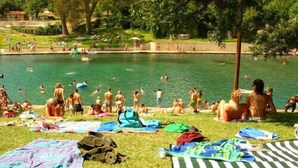 Et poolområde med folk, der svømmer og solbader.