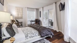 Et soveværelse med seng, sengebord, lampe og udsigt ud.