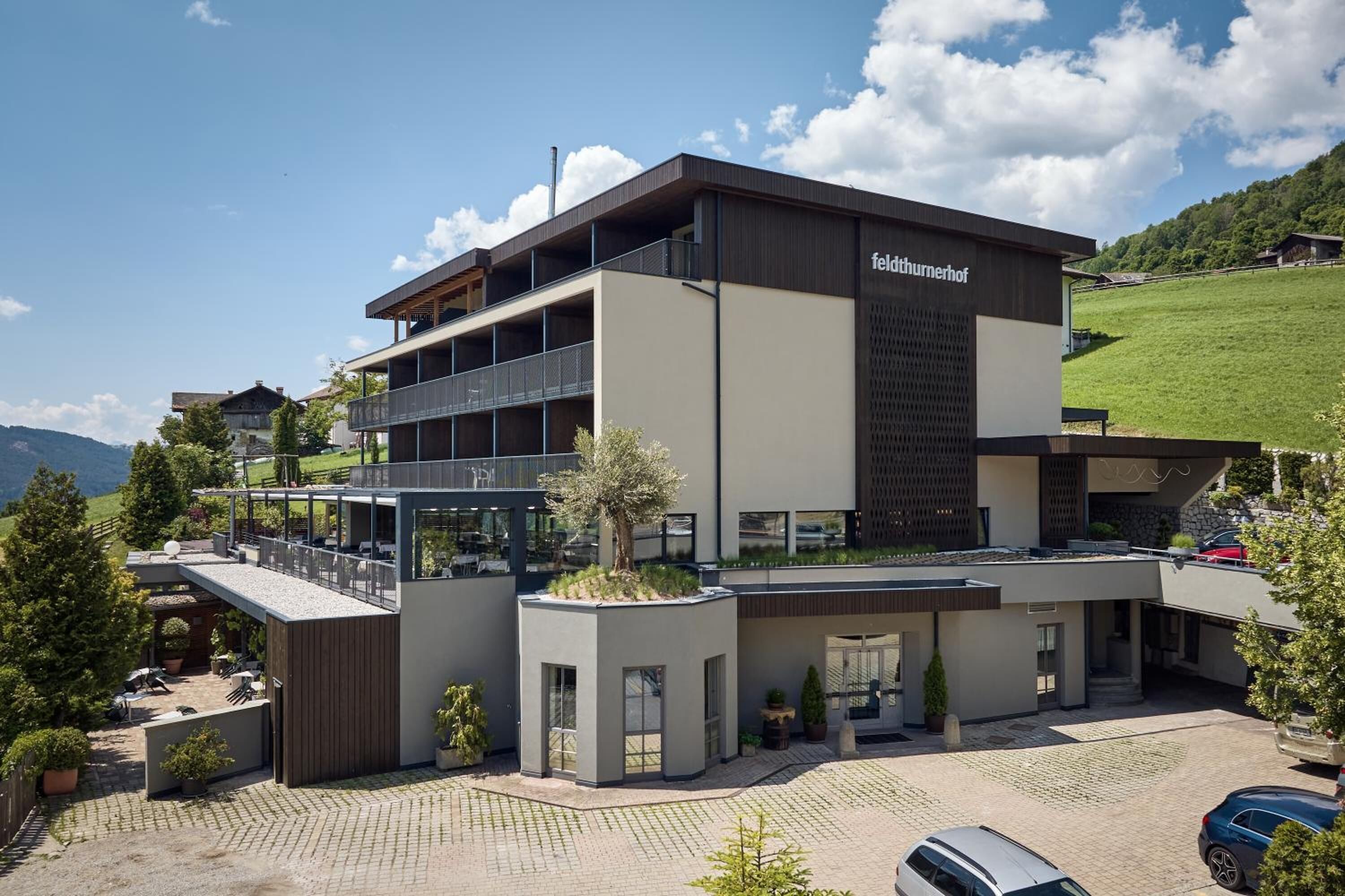 Ein modernes Hotel mit zweistöckiger Bauweise, Außenbereich mit Sitzgelegenheiten und einem Parkplatz.