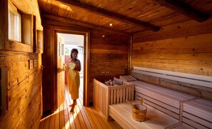 Een houten sauna met banken en een houten emmer.