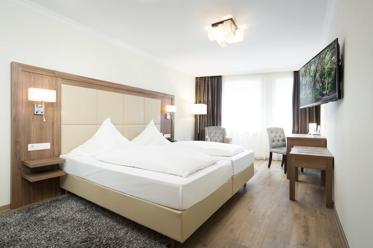 Une chambre d’hôtel avec un grand lit, des lampes de chevet, un bureau et une télévision.