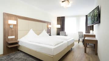 Une chambre d’hôtel avec un grand lit, des lampes de chevet, un bureau et une télévision.