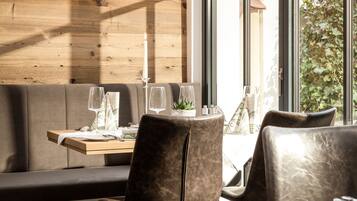 A cozy restaurant interior with wooden walls, a large window, and a table set for two.