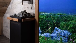 Un baño con pared de piedra, techo de madera y lavamanos negro.