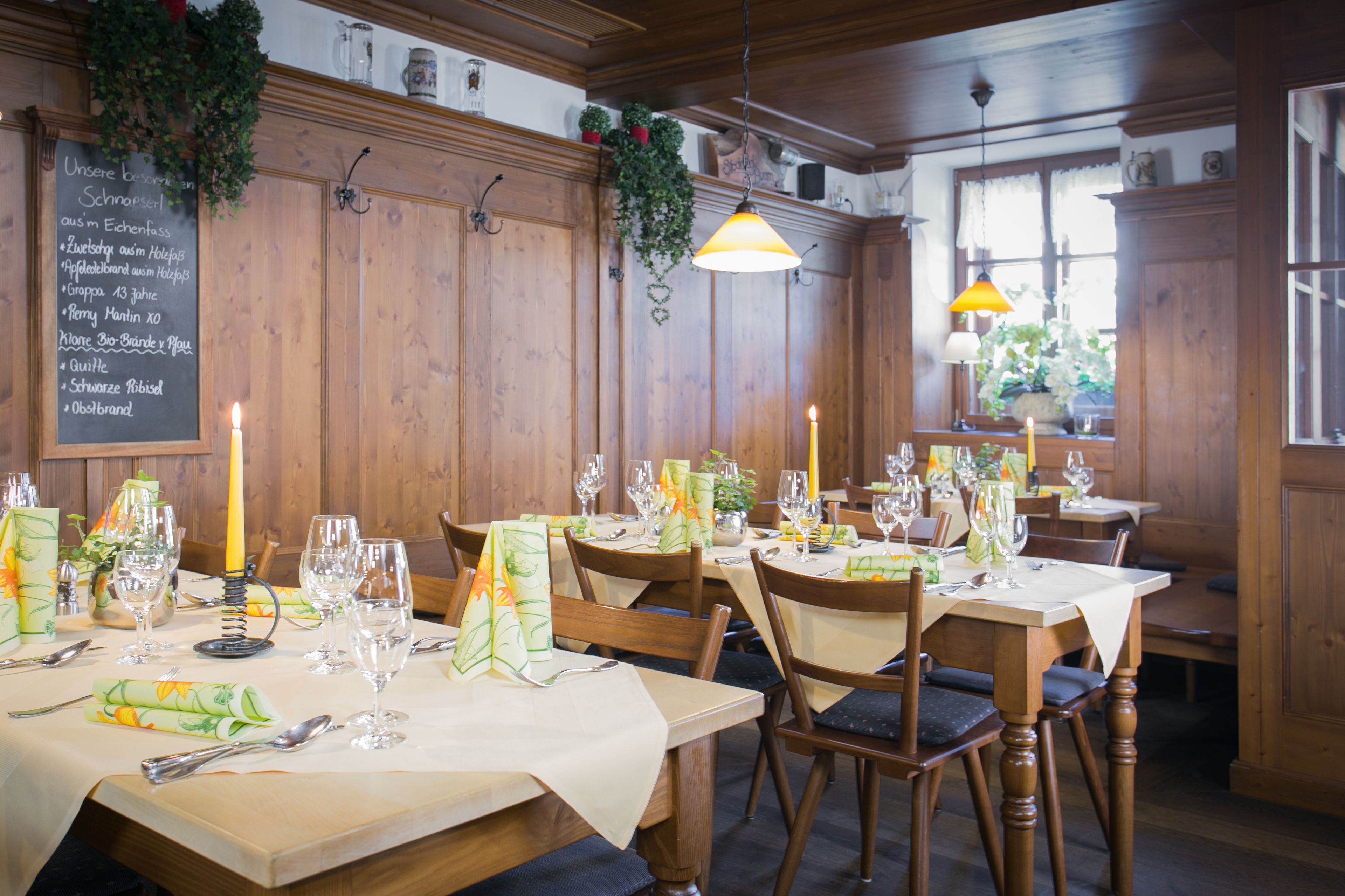 A restaurant with wooden paneling, tables set with wine glasses, plates, and cutlery.