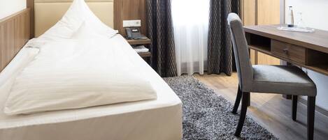 Una habitación de hotel con una cama, un escritorio, una silla, una lámpara y un cuadro en la pared.