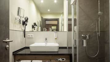 A modern bathroom with a large mirror, a sink, and a shower.