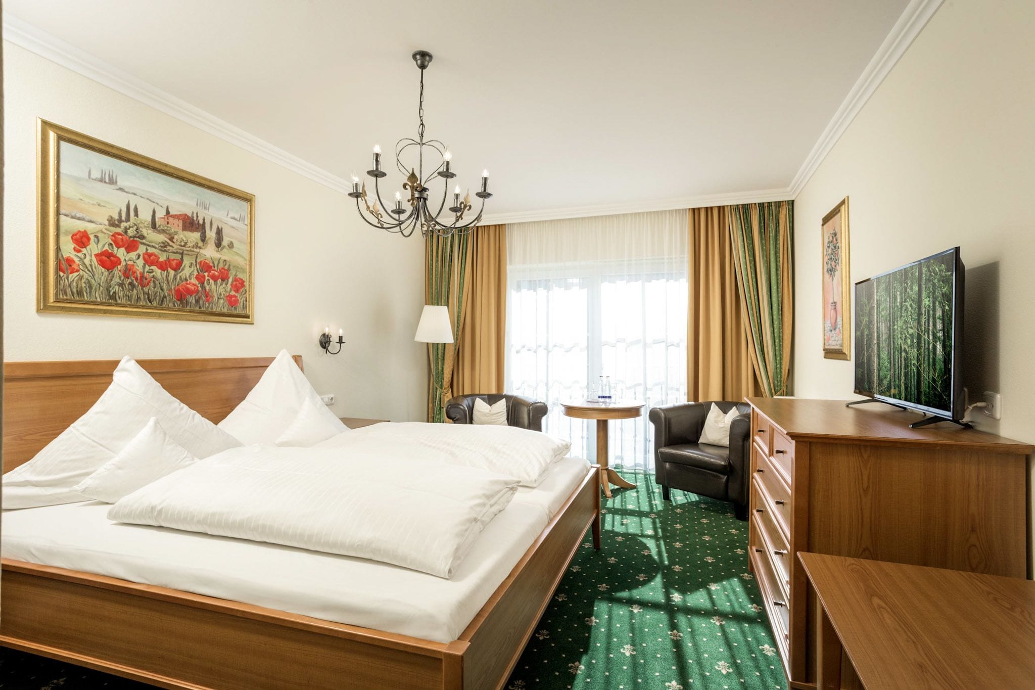 Habitación de hotel con una cama grande, un escritorio, un televisor y un cuadro en la pared.