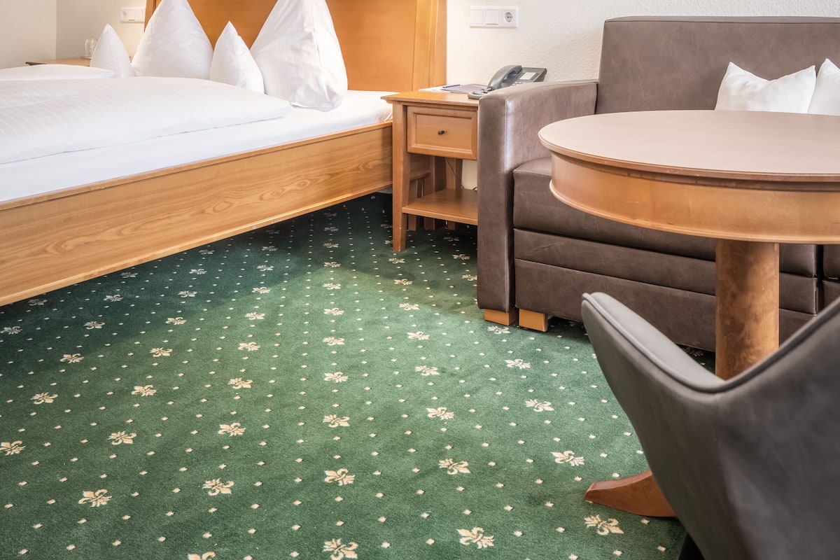 Une chambre d’hôtel avec un lit, un bureau, une chaise et une petite table.