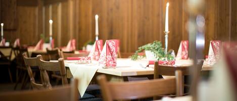 A restaurant with wooden walls and tables set with red napkins and candles.