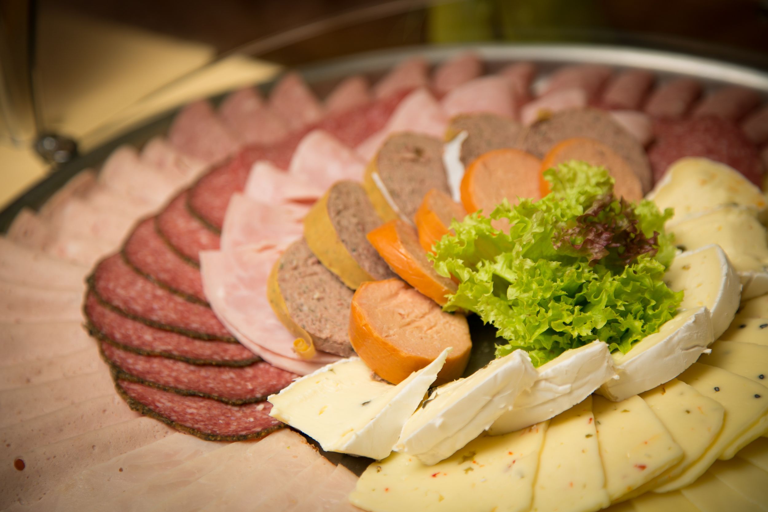 Ein Teller mit verschiedenen Aufschnitten von Fleisch und Käse.