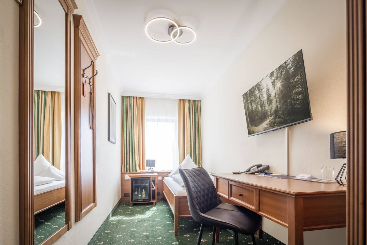 Une chambre d’hôtel avec un lit, un bureau, une chaise et un grand tableau au mur.