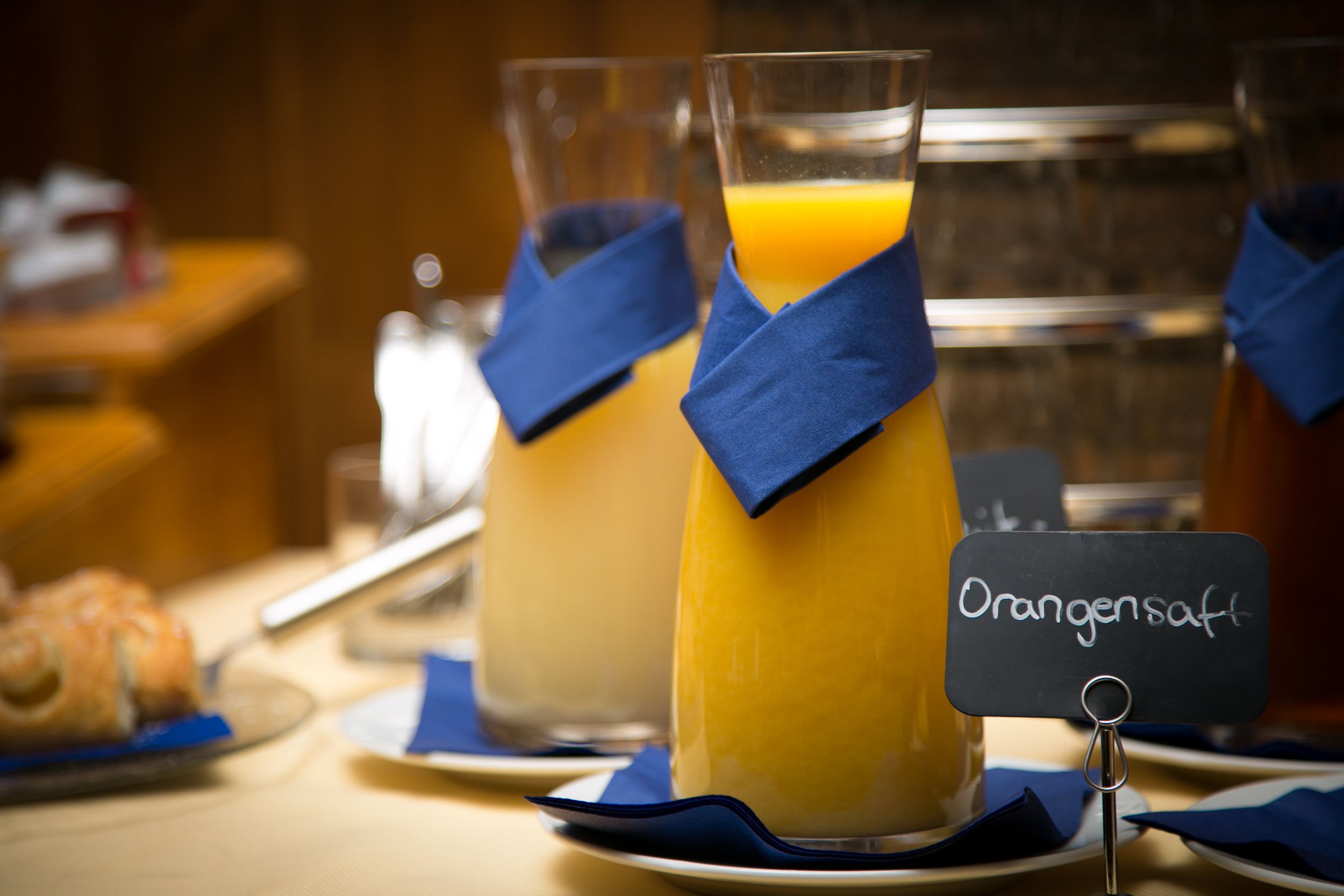 Un bufé de desayuno con zumo de naranja y bollería.