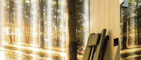 A room with a large forest mural, two massage chairs, and a wooden ceiling.