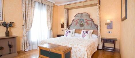 Un dormitorio con una cama grande, un cofre de madera y una mesita de noche con lámpara.