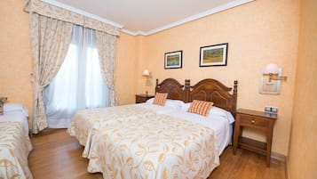 A hotel room with a large bed, two bedside tables, a nightstand, a window with curtains, and two wall-mounted lamps.
