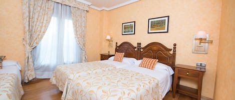 A hotel room with a large bed, two bedside tables, a nightstand, a window with curtains, and two wall-mounted lamps.