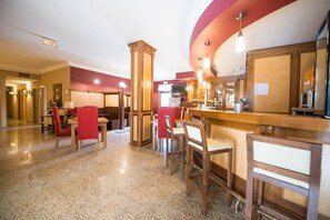En hotellobby med en bardel, sittplatser och en receptionsdisk.