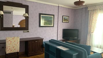 Ein Wohnzimmer mit einem blauen Sofa, einem Fernseher, einer Kommode und einem Spiegel.