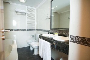 Ein Badezimmer mit Badewanne, zwei Toiletten, einem Waschbecken und einem großen Spiegel.